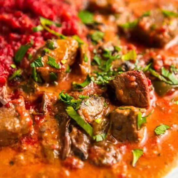 A close-up shot of Beef Stroganoff, capturing the creamy texture of the slow-cooked beef, the vibrant colors of the beetroot and sweet potato mash, and the fresh garnish of spring onions. The dish’s silky sauce and rich ingredients take center stage in this detailed view.